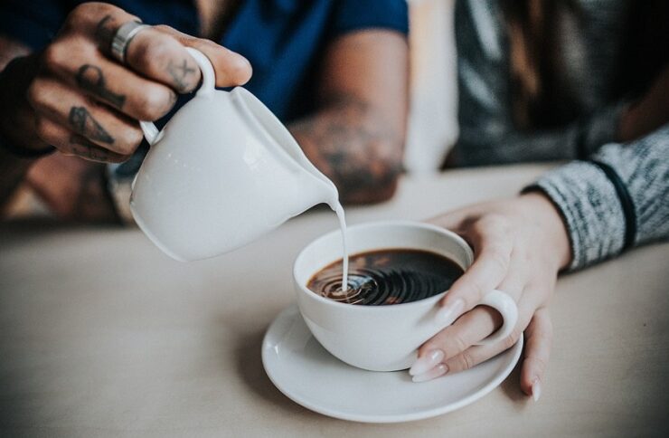 Milich wird in den Kaffee geschüttet